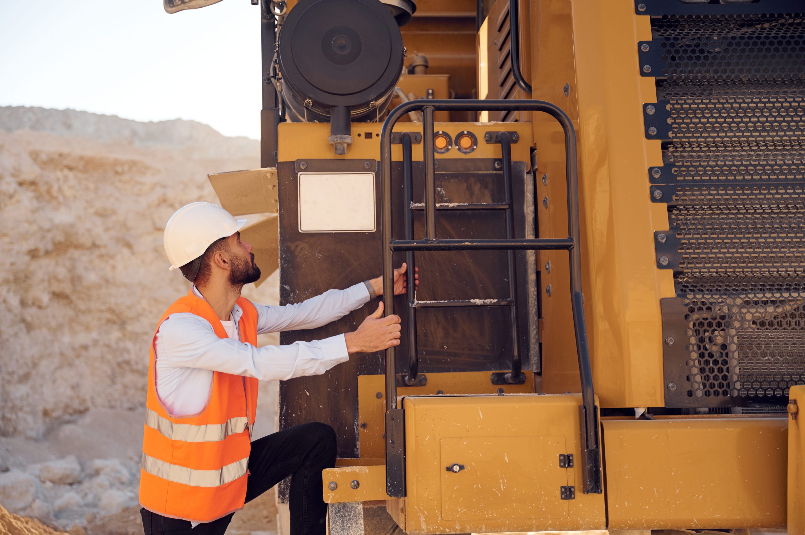 construction worker inspecting heavy machinery during construction site safety inspection