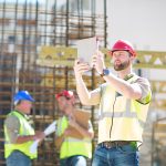 construction worker performing digital safety inspection on construction site using tablet