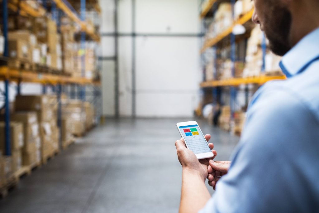 Site manager checking a digital asset register on a phone to track tools and equipment